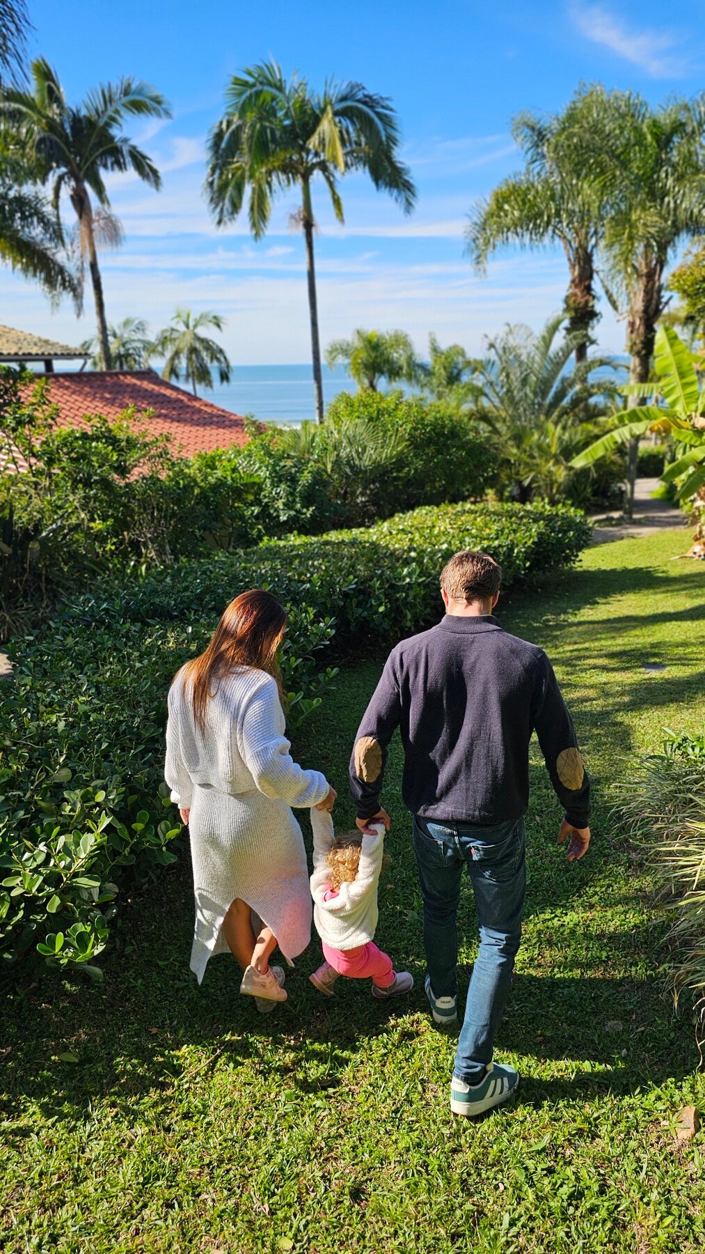 Família caminhando em meio à natureza com vista para o mar